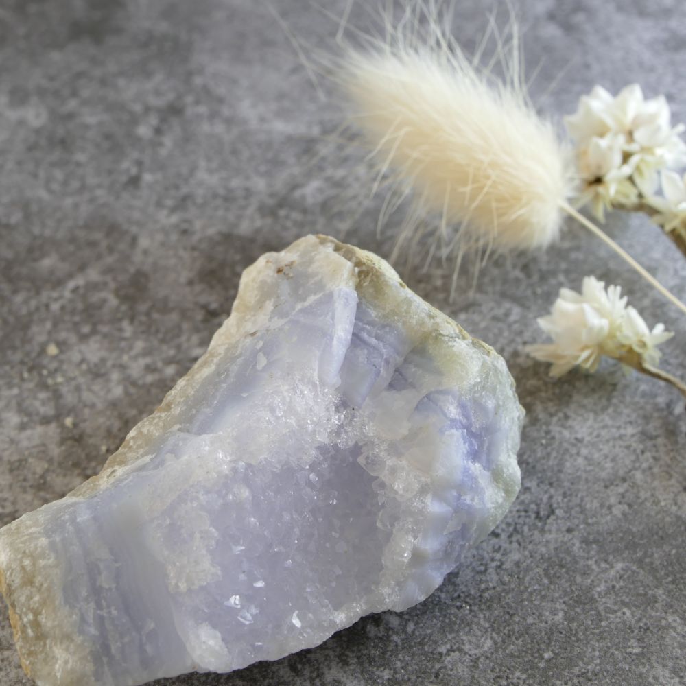 Macro photo detailing the delicate banding of blue lace agate intertwined with clear quartz crystals. Highlights the natural beauty and unique mineral composition of this raw specimen.