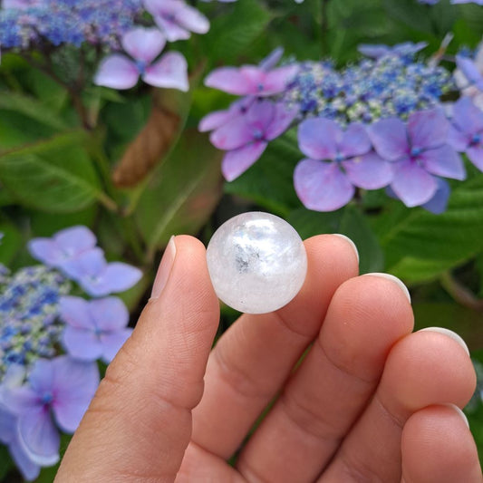 Dumi's Crystals | Clear Quartz with Inclusions Mini Sphere (20mm) | A close-up view of a captivating Clear Quartz Mini Sphere (20mm) with mesmerizing inclusions. This "Master Healer" crystal radiates powerful energy for clarity, focus, and spiritual growth.