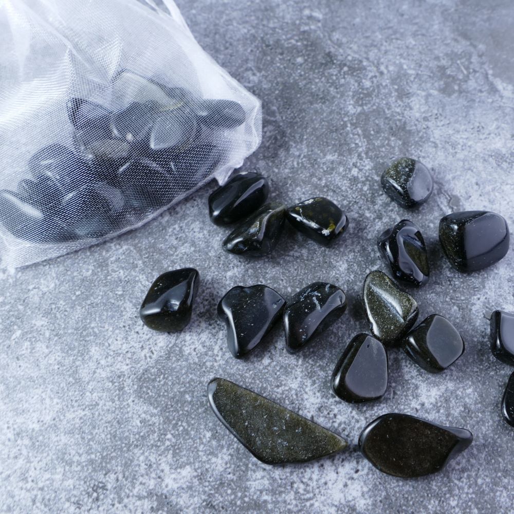 Dumi's Crystals | Gold Obsidian Chips (1-2cm) | Close-up of a collection of genuine Gold Obsidian chips, highlighting their distinctive golden sheen and variations in size and texture. Gold Obsidian is revered for its ability to shield against negativity, promote inner strength, and foster spiritual growth.