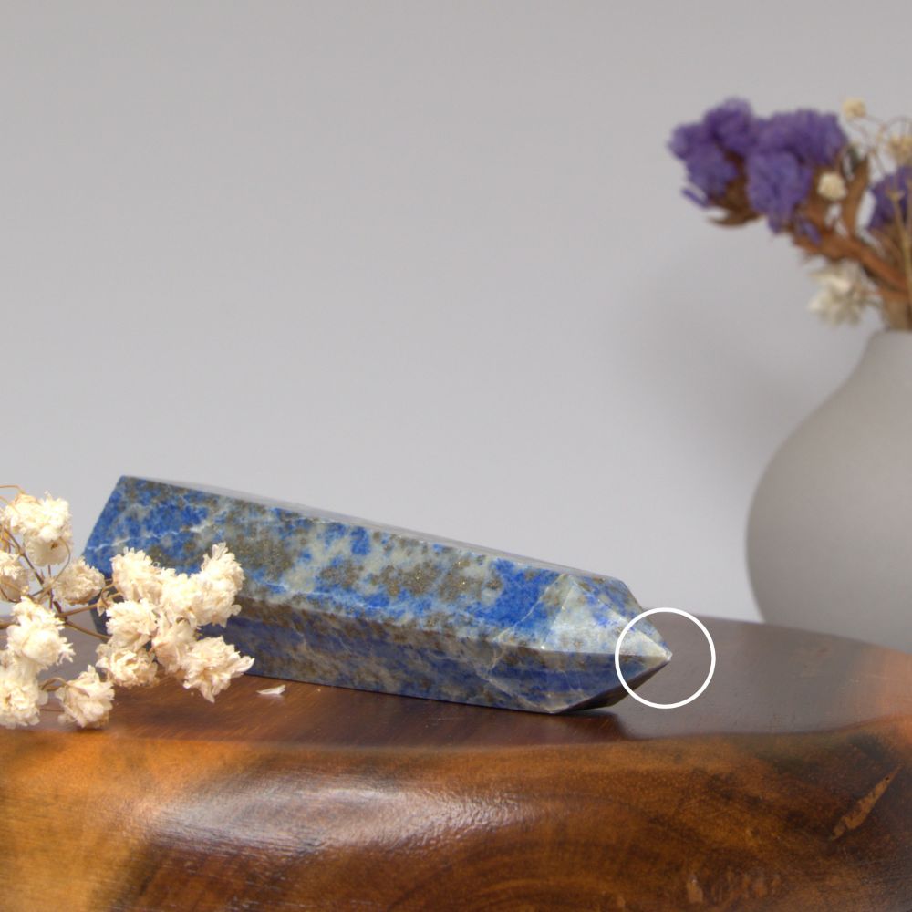 lapis lazuli tower on a wooden surface with flowers and a vase in the background