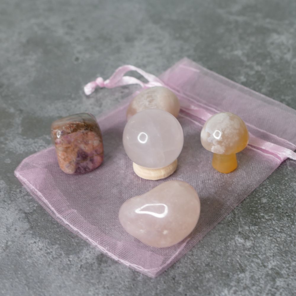 Set of crystal stones on a pink drawstring bag against a gray background