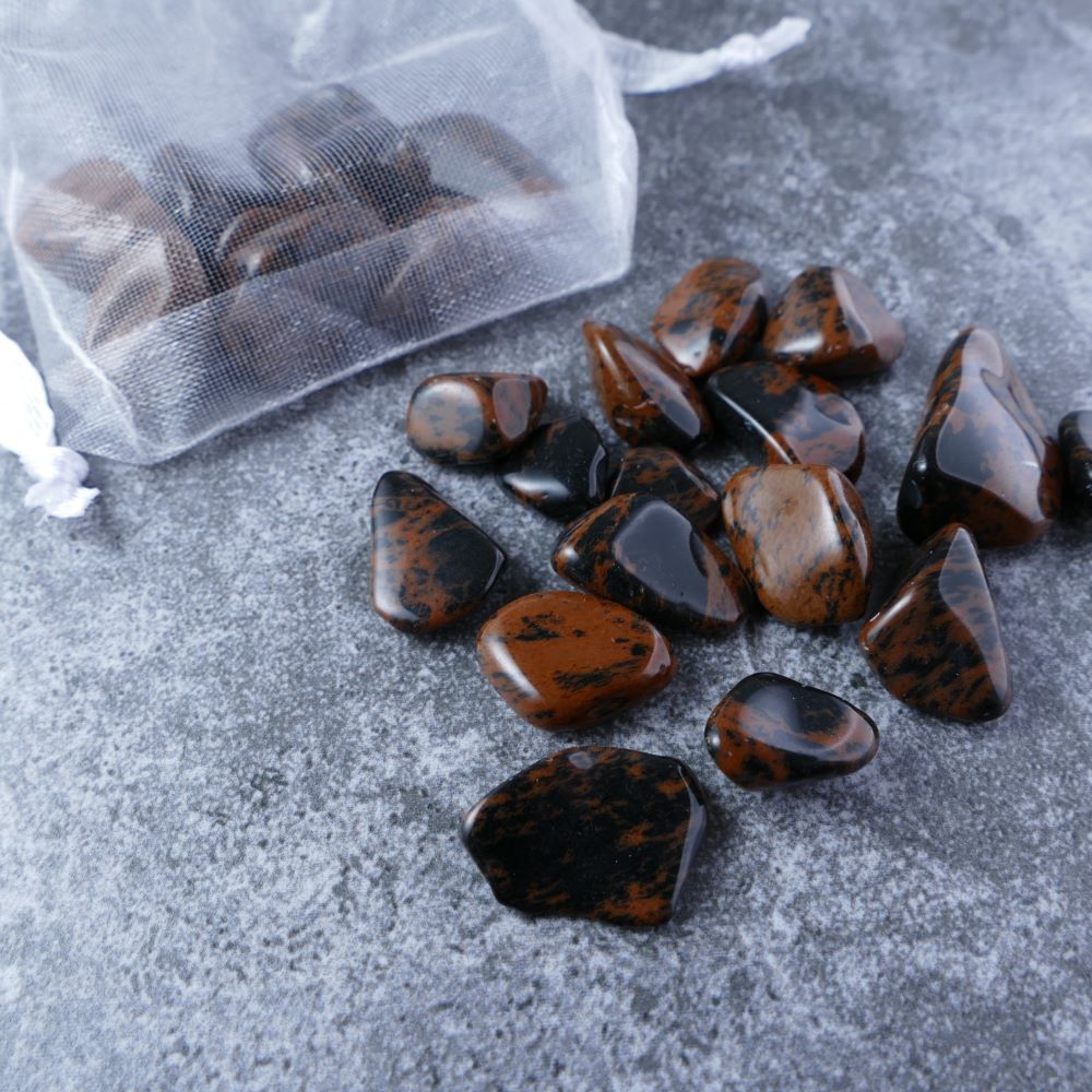 Dumi's Crystals | Mahogany Obsidian Chips (1-2.5cm) | Close-up of a collection of genuine Mahogany Obsidian chips, highlighting their rich brown color and captivating variations in pattern. Mahogany Obsidian is revered for its ability to shield against negativity, promote grounding, and encourage spiritual growth.