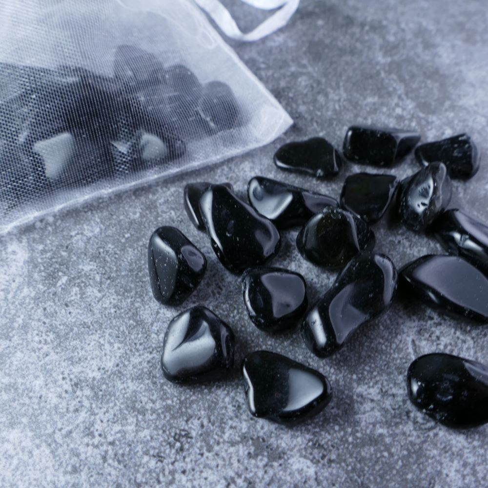 Dumi's Crystals | Black Obsidian Chips (1-1.5cm) | Close-up of a collection of genuine Black Obsidian chips, highlighting their deep black color and smooth texture. Black Obsidian is revered for its ability to shield against negativity, promote grounding, and empower the spirit.