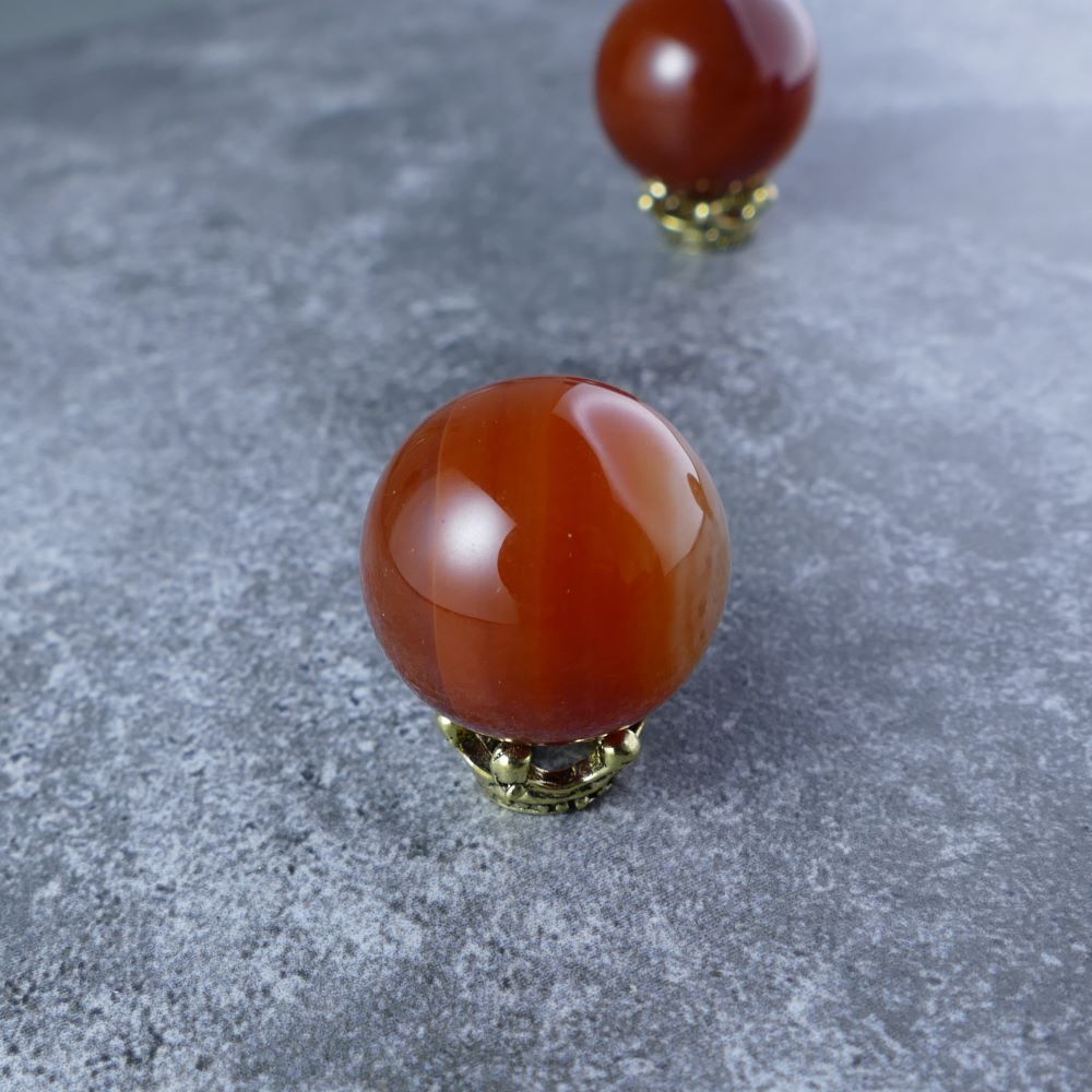 Unleash Inner Strength with Red Agate Mini Sphere (20mm) | Dumi's Crystals | Invite the anchoring energy of Red Agate into your life! This 20mm sphere is thought to promote emotional balance, courage, and a sense of security.