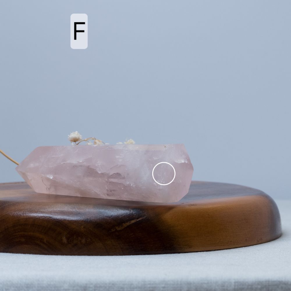 Rose quartz crystal on a wooden stand with a blurred background