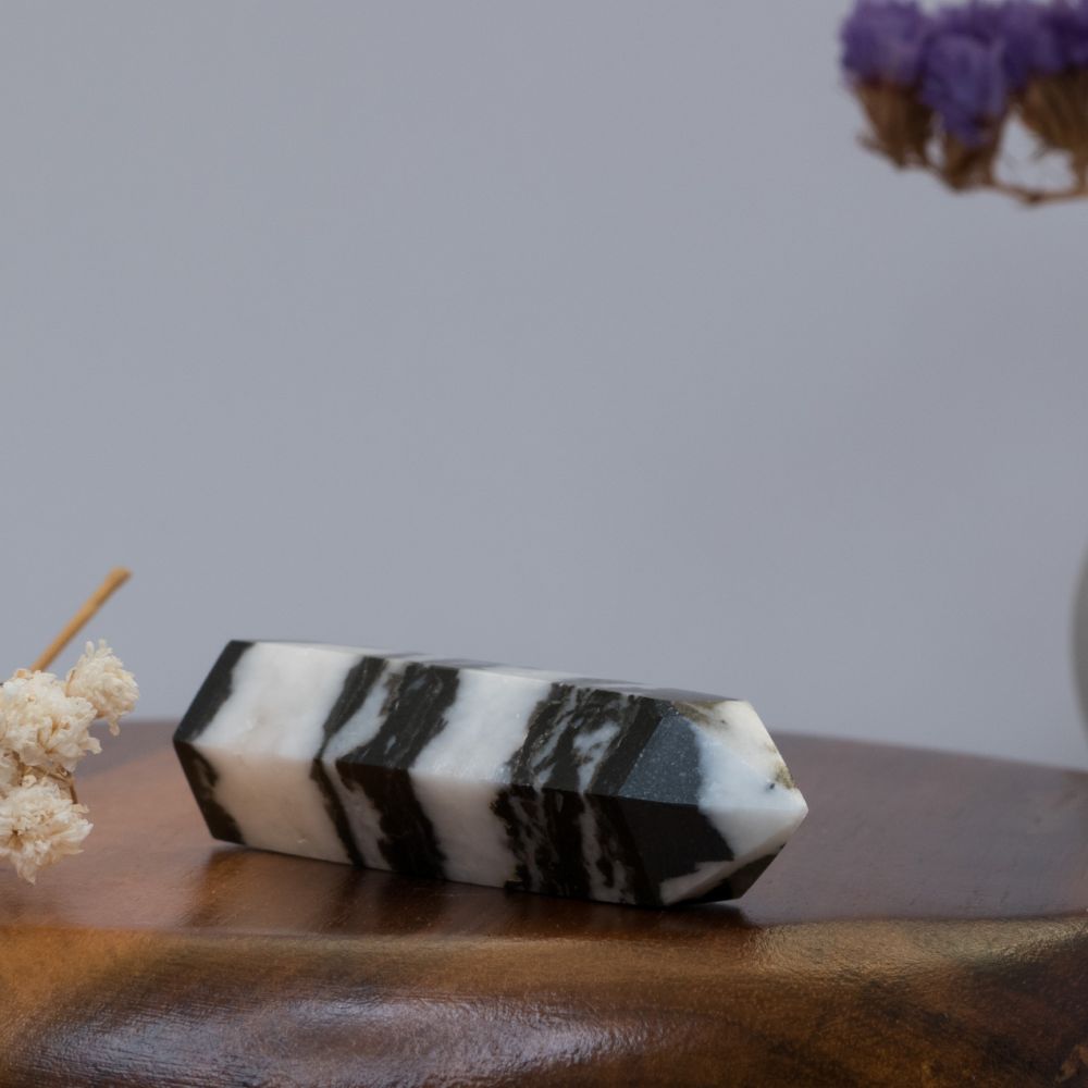 Black and white striped crystal tower on a wooden surface with dried flowers in the background
