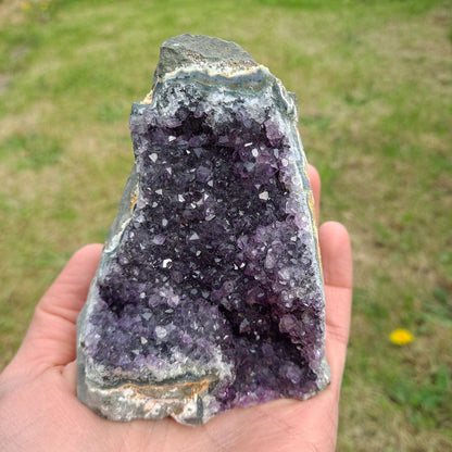 Dumi's Crystals | Amethyst Cluster (Portable, 9cm) in hand (side view) | Feel the intricate crystals of this Amethyst Cluster (9 x 7.6 x 7.6cm) as you hold it in your hand. Let its gentle energy wash over you, promoting relaxation and emotional balance.