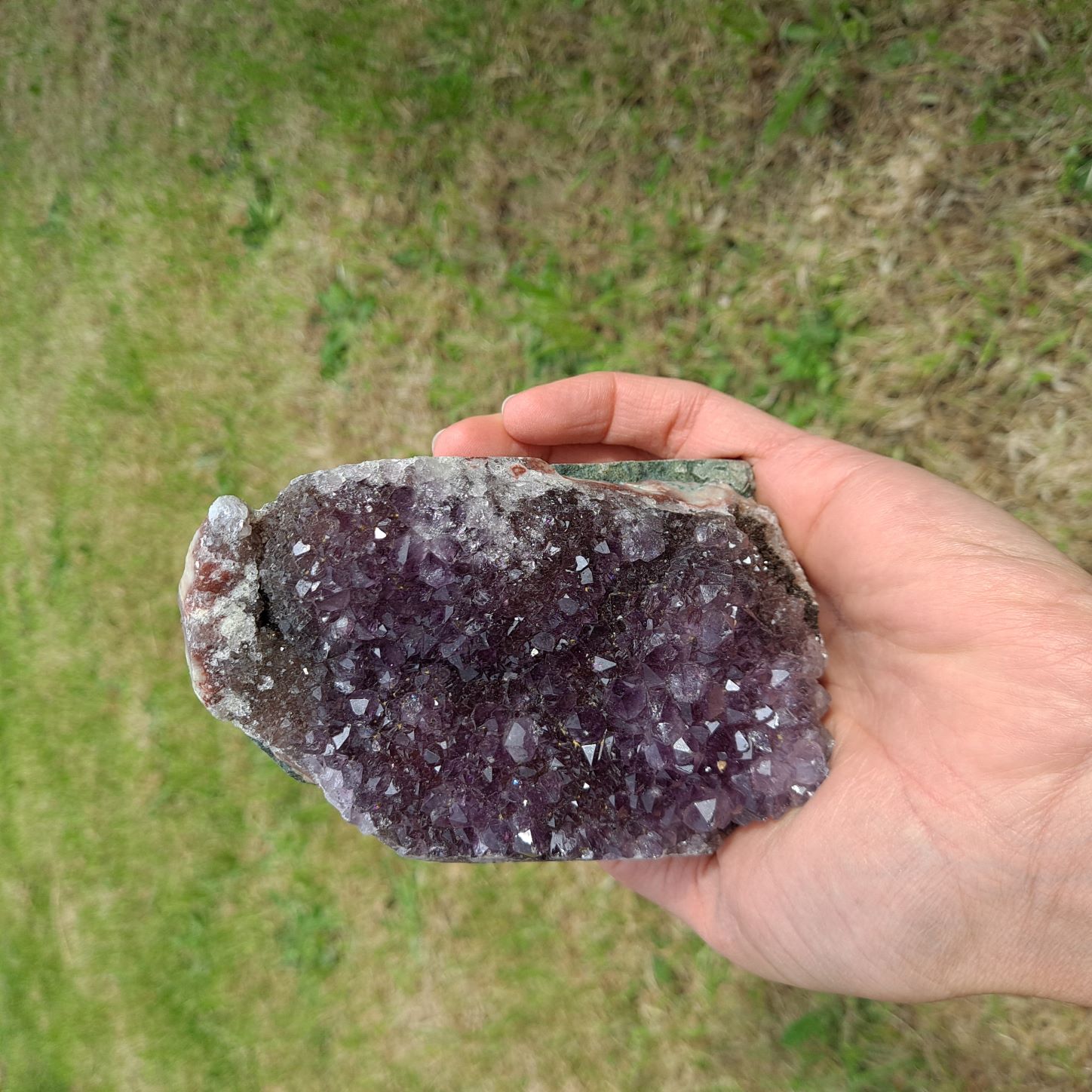 Dumi's Crystals | Amethyst Cluster (10.6cm, Striking) in hand (side view) | Feel the intricate crystals of this Amethyst Cluster (10.6 x 6.3 x 6.9cm) as you hold it in your hand. Its comfortable size allows you to connect with its calming energy, promoting relaxation and emotional balance.