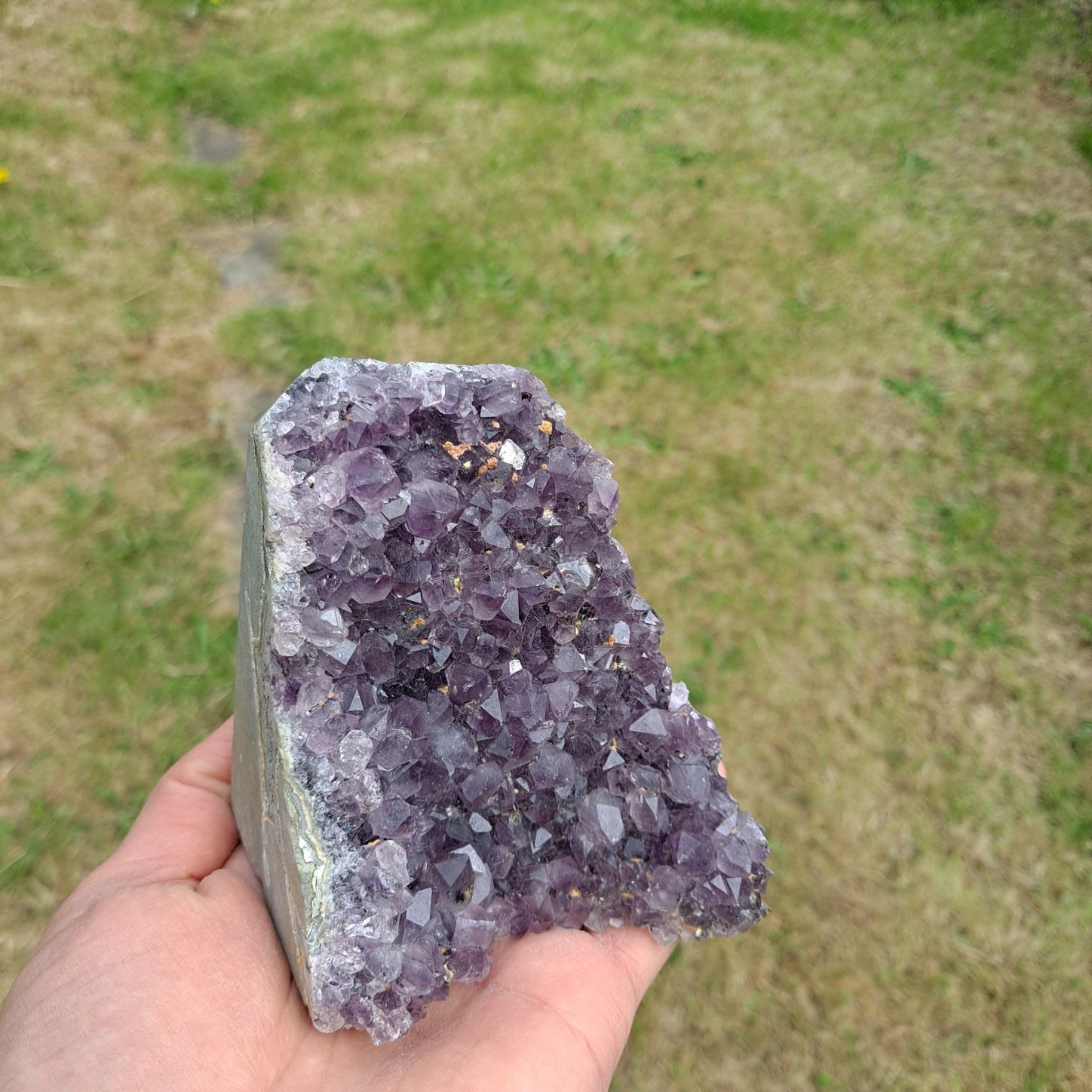 Dumi's Crystals | Amethyst Cluster (Portable, 8.9cm) in hand (side view) | Feel the intricate crystals of this Amethyst Cluster (8.9 x 6.3 x 8.9cm) as you hold it in your hand. Let its gentle energy wash over you, promoting relaxation and emotional well-being.