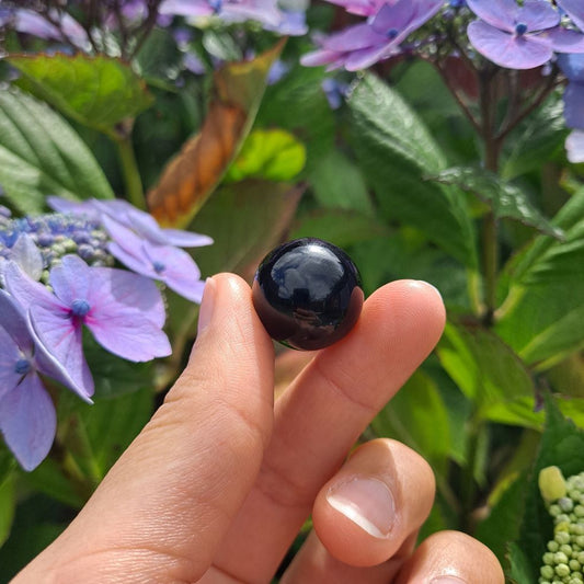 Dumi's Crystals | Black Obsidian Mini Sphere (20mm) | A close-up view of a captivating Black Obsidian Mini Sphere, showcasing its deep, glossy sheen. This 20mm sphere offers a powerful shield of protection against negativity while promoting inner healing, growth, and self-discovery.