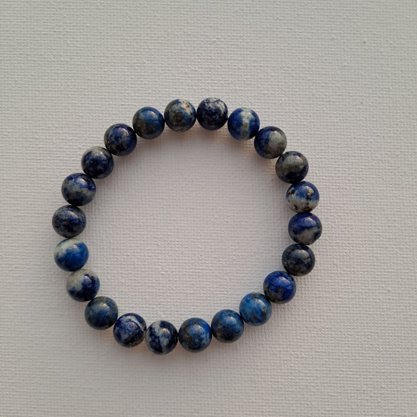 Dumi's Crystals | Lapis Lazuli Stretch Bracelet (8mm) | Close-up of a handcrafted bracelet featuring genuine Lapis Lazuli in 8mm beads. The captivating blend of blue hues with golden pyrite flecks is known to activate the third eye chakra and promote mental clarity.