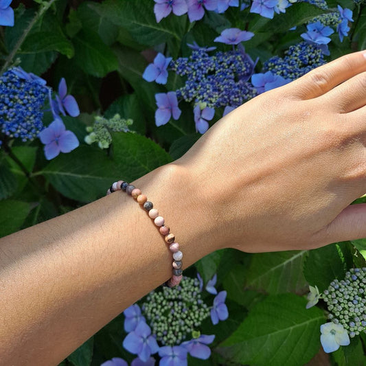 Dumi's Crystals | 4mm Rhodonite Stretch Bracelet (7 Inch) | Showcasing the delicate beauty of 4mm Rhodonite beads on a wrist. This bracelet promotes emotional healing, self-love, and fosters compassion. Rhodonite, the stone of compassion, is known for its calming pink hues.