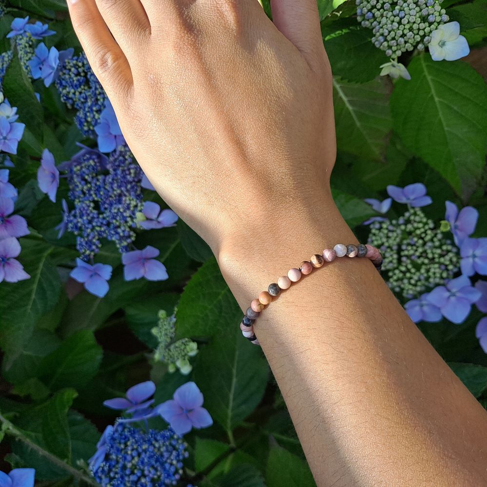 Dumi's Crystals | 4mm Rhodonite Stretch Bracelet (7 Inch) | Showcasing the delicate beauty of 4mm Rhodonite beads on a wrist. This bracelet promotes emotional healing, self-love, and fosters compassion. Rhodonite, the stone of compassion, is known for its calming pink hues.