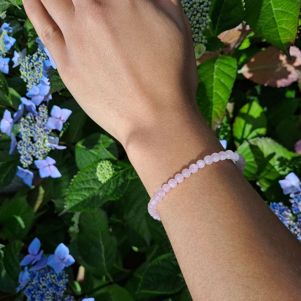 Dumi's Crystals | 4mm Rose Quartz Stretch Bracelet (7 Inch) | Showcasing the delicate beauty of 4mm Rose Quartz beads on a wrist. This bracelet promotes emotional healing, self-love, and fosters compassion. Rose Quartz, the stone of unconditional love, is known for its soft pink hues.