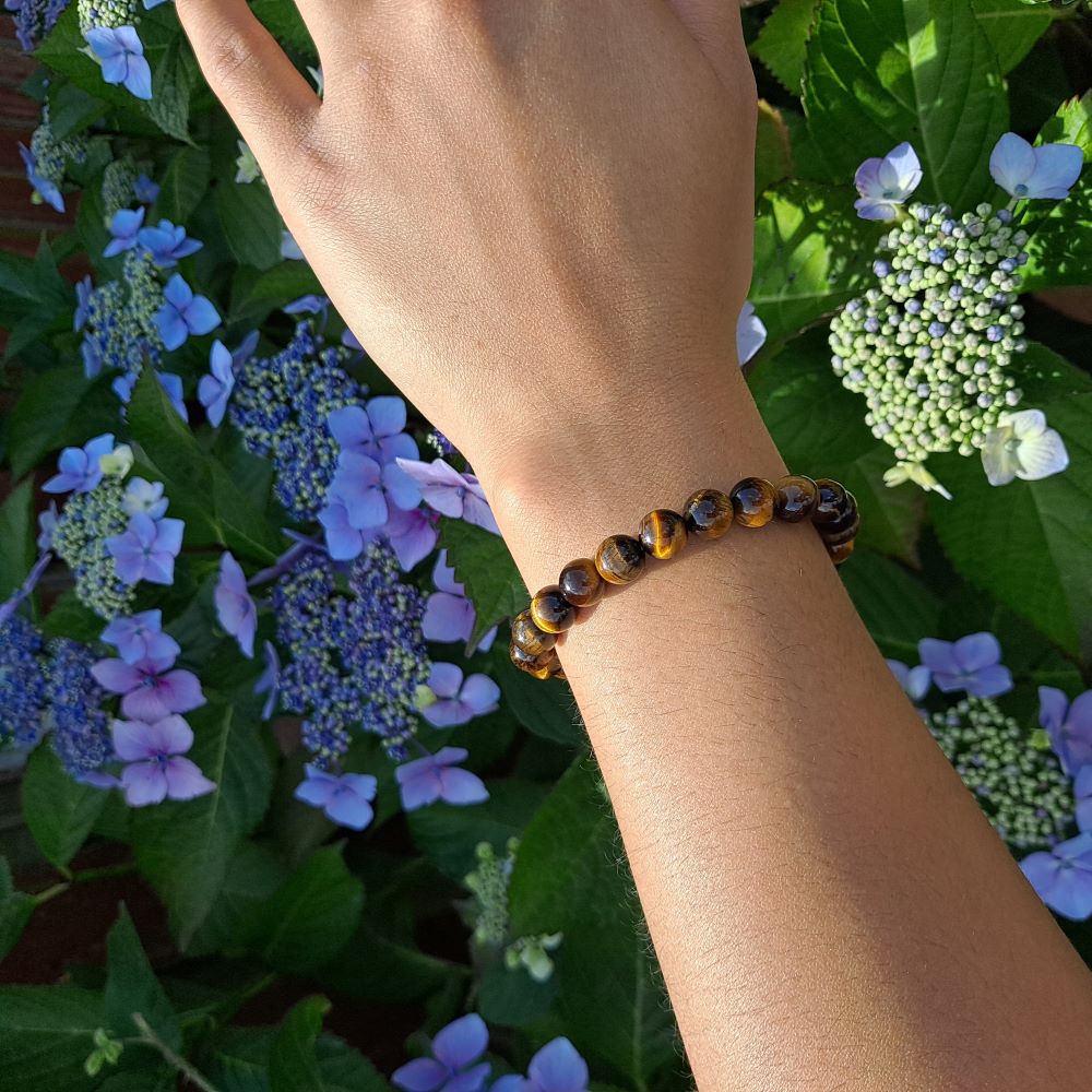 Dumi's Crystals | Tiger's Eye Stretch Bracelet (7 Inch with 8mm Beads) | Showcasing the captivating beauty of bold 8mm Tiger's Eye beads on a wrist. This bracelet promotes strength, confidence, protection, mental clarity, and abundance. Tiger's Eye, the stone of courage and protection, is known for its golden-brown hues with chatoyant streaks.