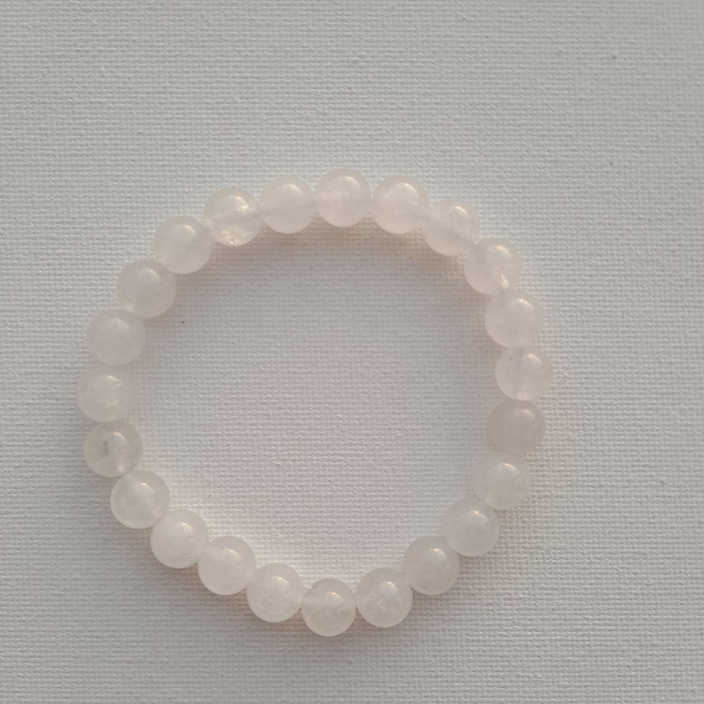 Dumi's Crystals | White Jade Stretch Bracelet (7 Inch with 8mm Beads) | Close-up of a handcrafted bracelet featuring genuine 8mm White Jade beads with a luminous glow. White Jade is known as the stone of peace and tranquility and is believed to promote inner peace, clarity of mind, spiritual growth, and emotional balance.