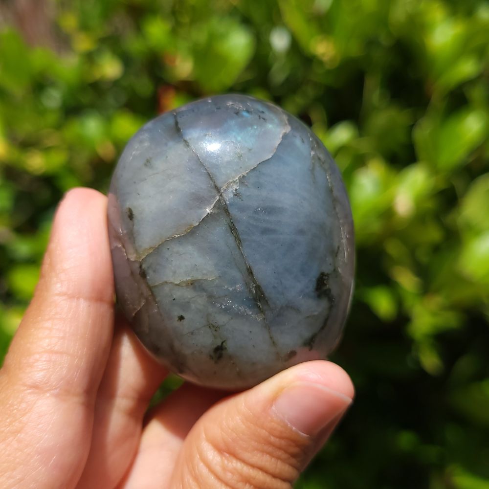 Hand holding a blue stone with a green blurred background