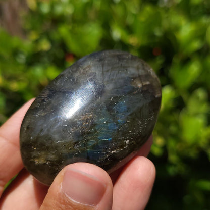 Person holding a labradorite stone with a blurred green background