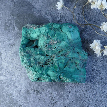 Embrace Change with Dumi's Crystals (8cm x 8.5cm x 1cm). Polished malachite slab reveals vibrant green alongside natural stone. Promotes healing, protection, and spiritual growth.  