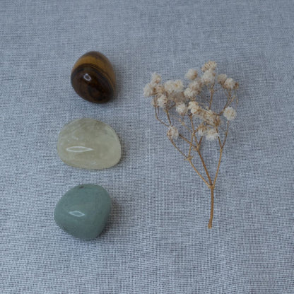 Three stones and a small branch of dried flowers on a textured fabric background