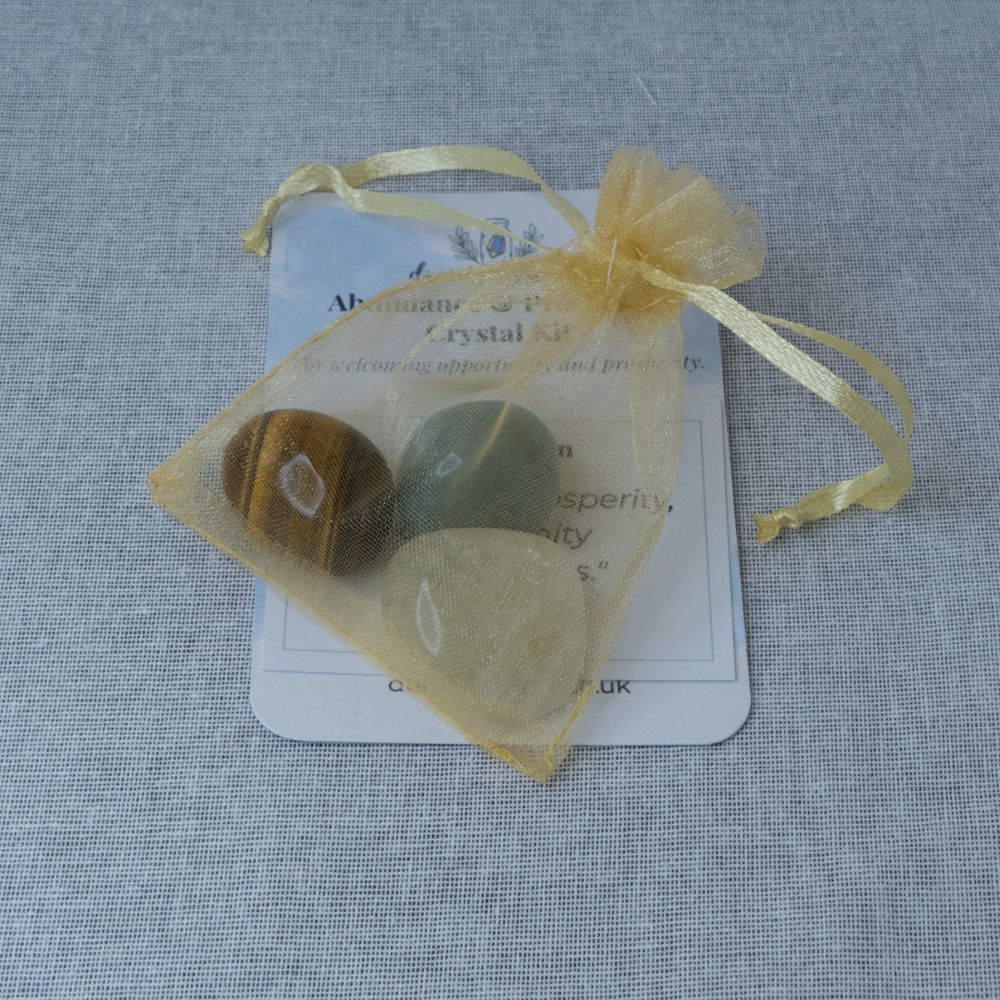 Crystal kit with stones in a yellow drawstring bag on a textured gray background