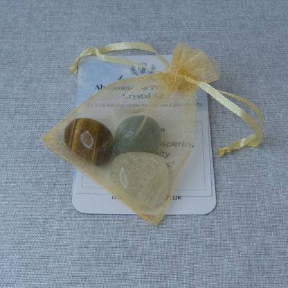 Crystal kit with stones in a yellow drawstring bag on a textured gray background