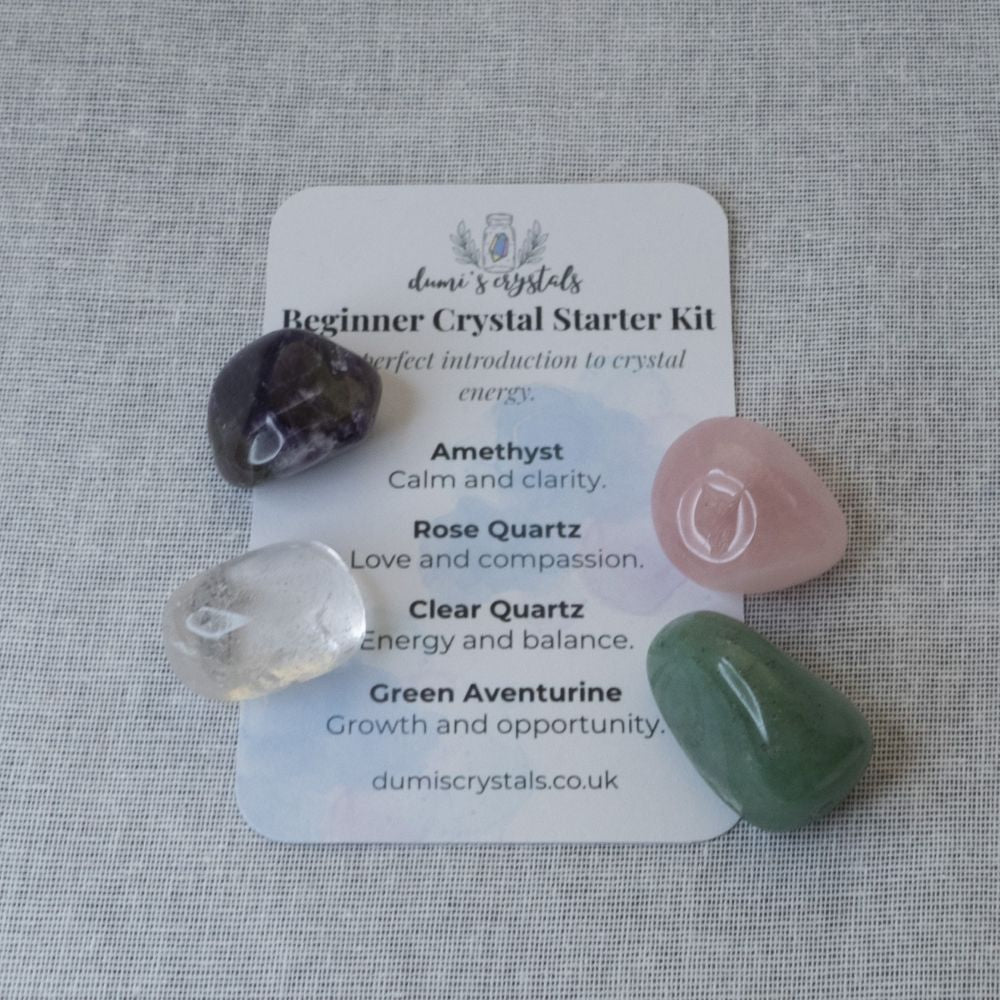 Crystal starter kit with amethyst, clear quartz, rose quartz and green aventurine on a card on a textured surface.