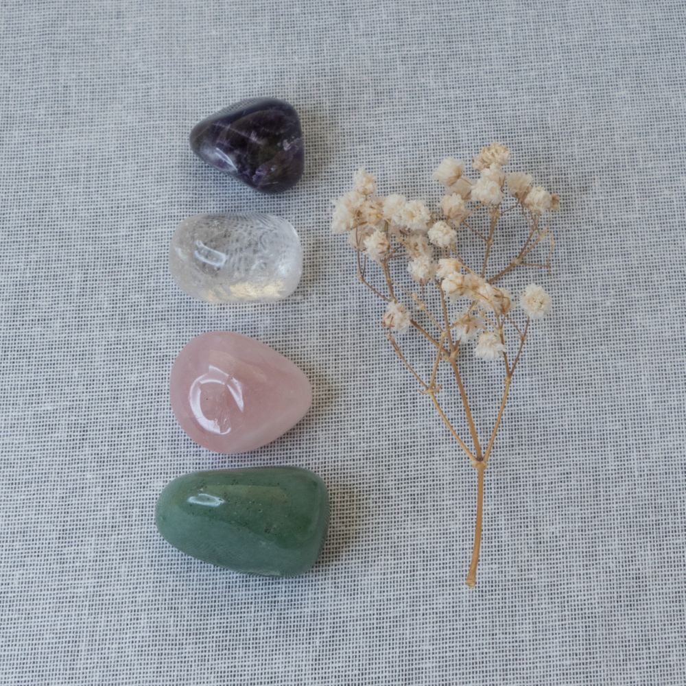 Collection of crystals and a small bouquet of dried flowers on a textured fabric background