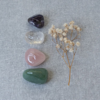 Collection of crystals and a small bouquet of dried flowers on a textured fabric background