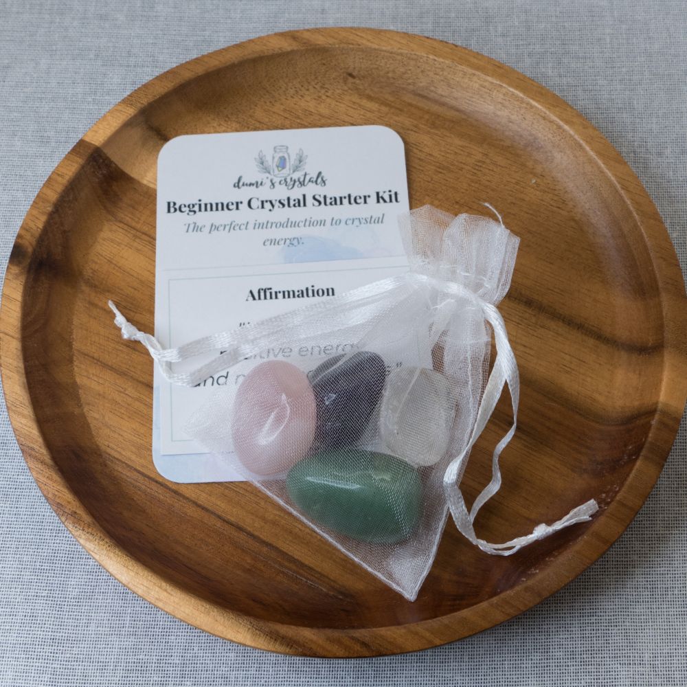 Crystal starter kit with stones and a card on a wooden plate