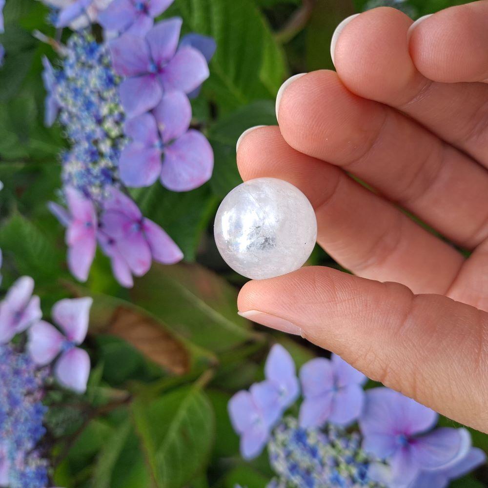 Dumi's Crystals | Clear Quartz with Inclusions Mini Sphere (20mm) | A close-up view of a captivating Clear Quartz Mini Sphere (20mm) with mesmerizing inclusions. This "Master Healer" crystal radiates powerful energy for clarity, focus, and spiritual growth.