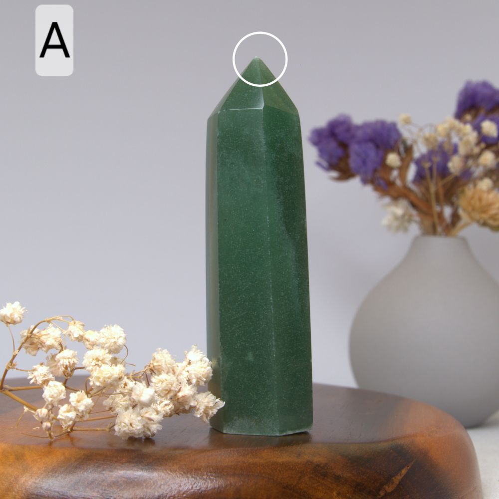 green aventurine tower on a wooden plate with a vase with dried flowers in the background 