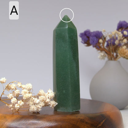 green aventurine tower on a wooden plate with a vase with dried flowers in the background 