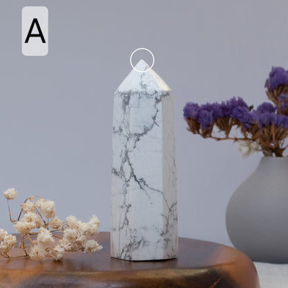 howlite obelisk on a wooden surface with flowers in the background