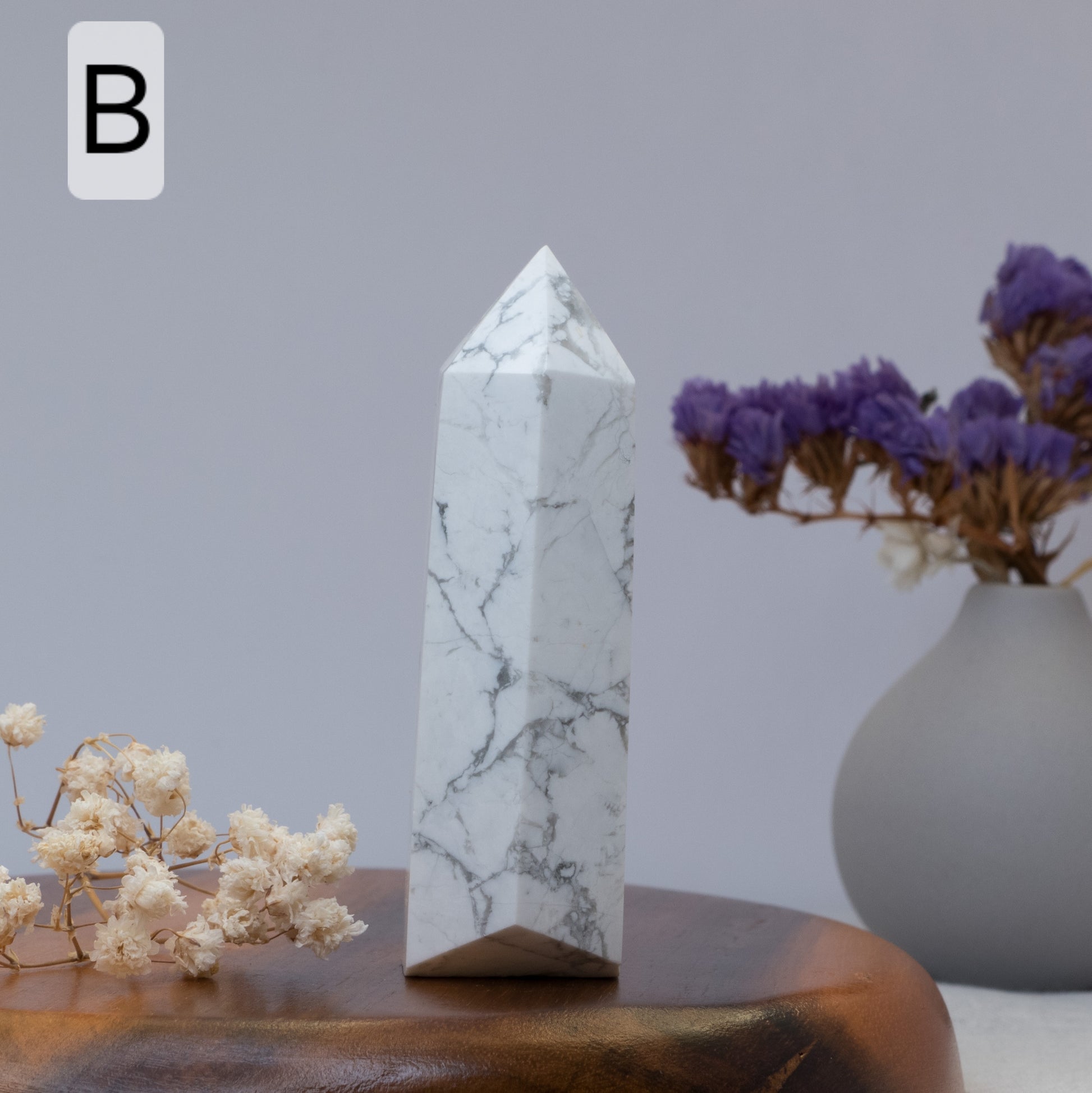 howlite on a wooden surface with flowers and a vase in the background