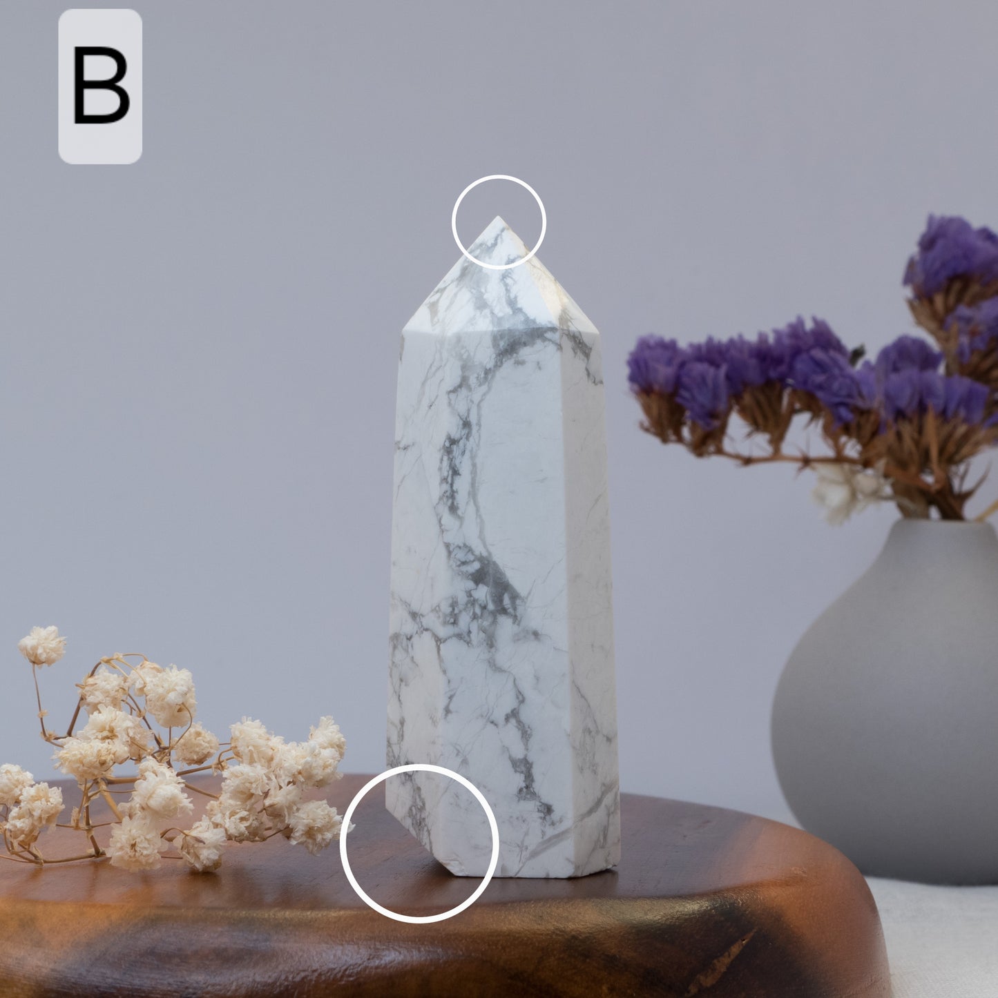 howlite tower on a wooden surface with a vase of purple flowers in the background.