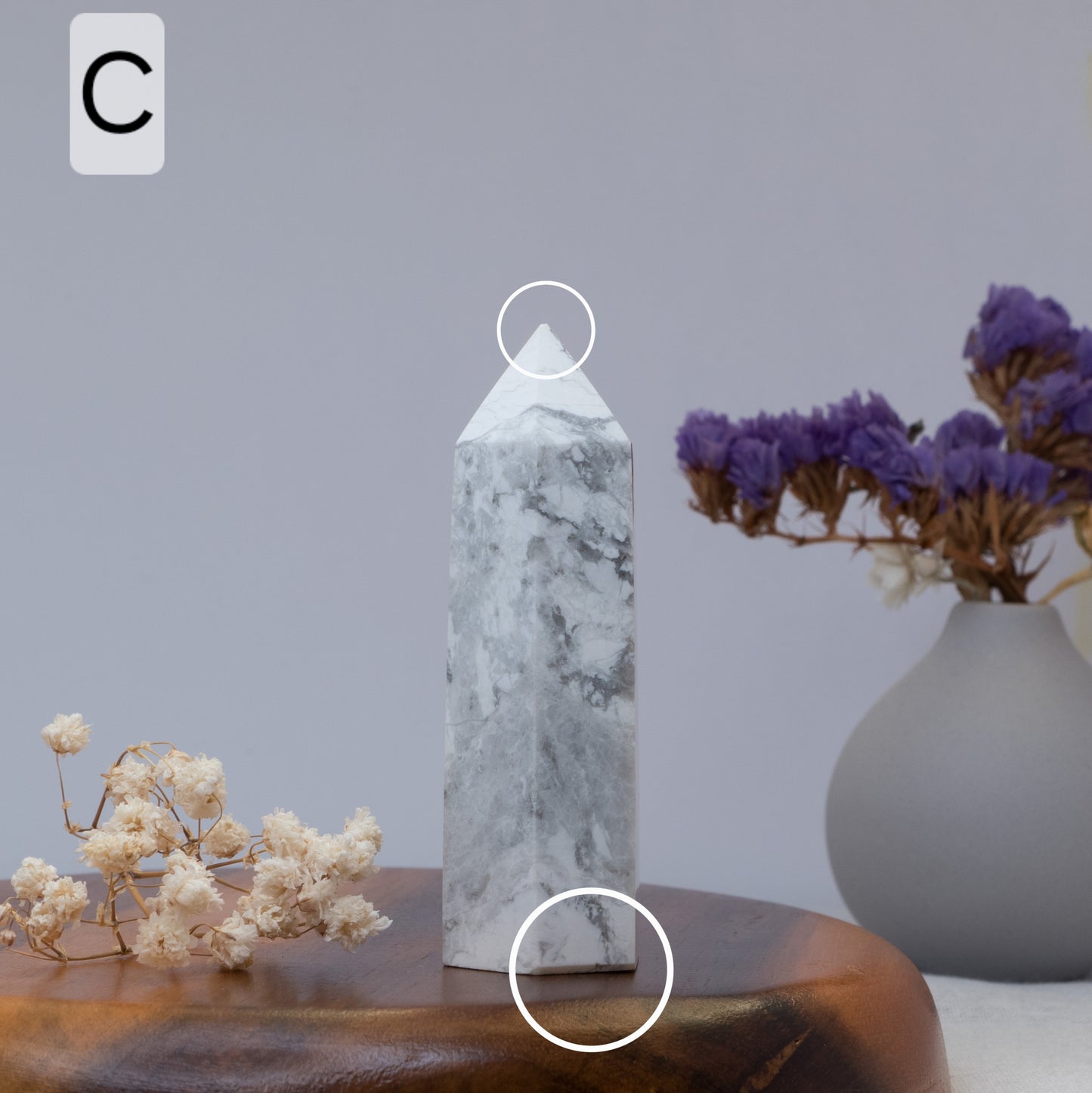 howlite obelisk on a wooden surface with flowers and a vase in the background