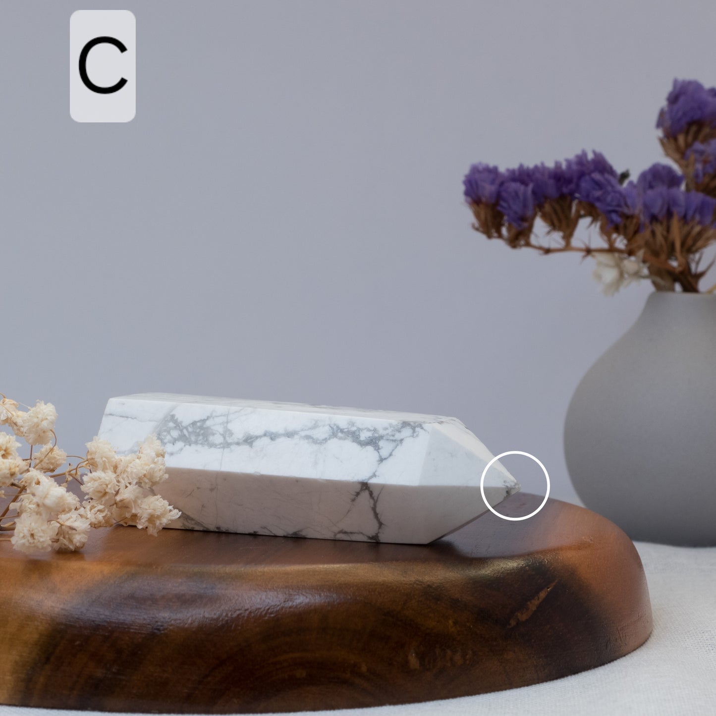 howlite tower on a wooden surface with a vase of purple flowers in the background.