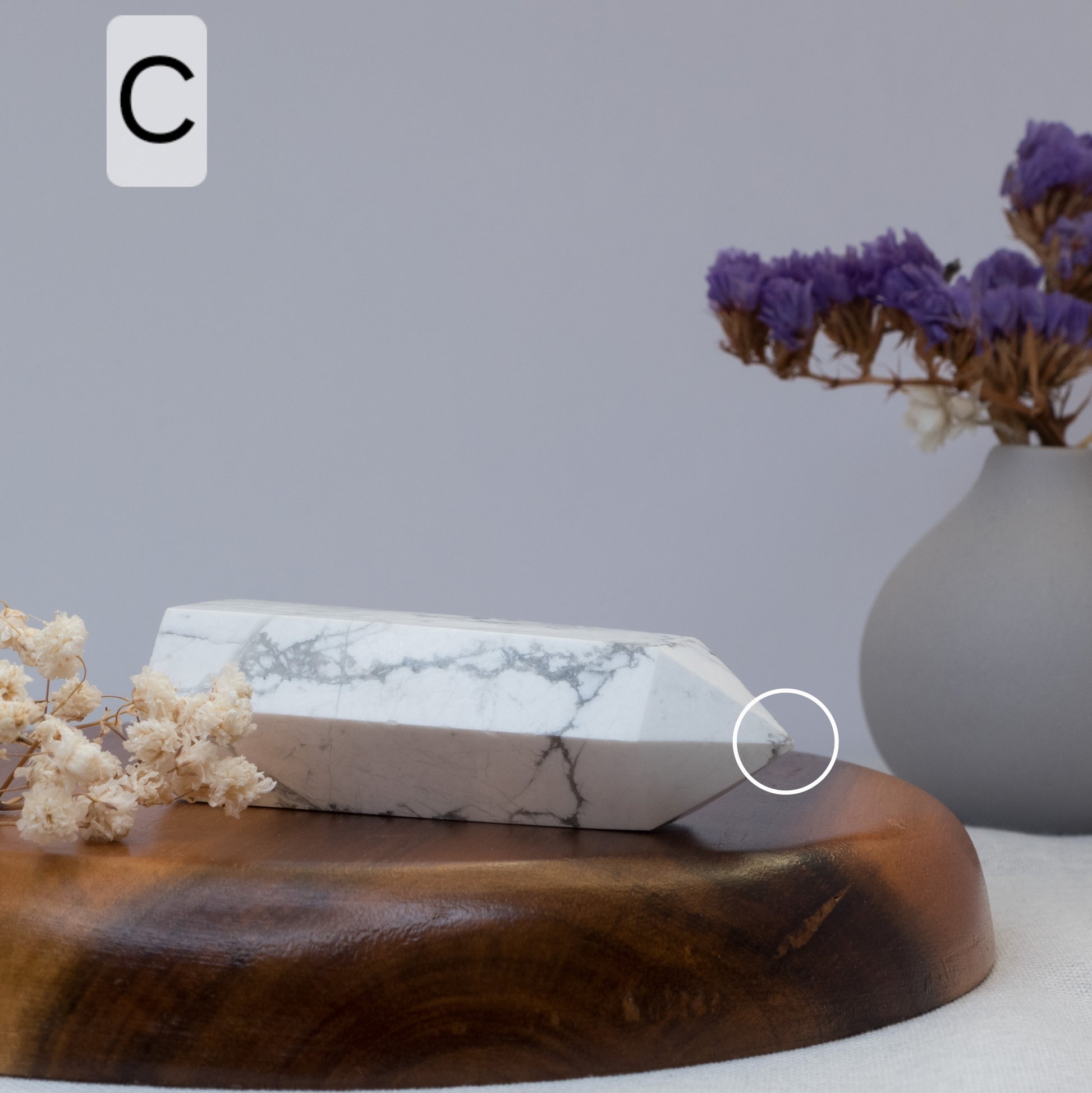 howlite tower on a wooden surface with a vase of purple flowers in the background.