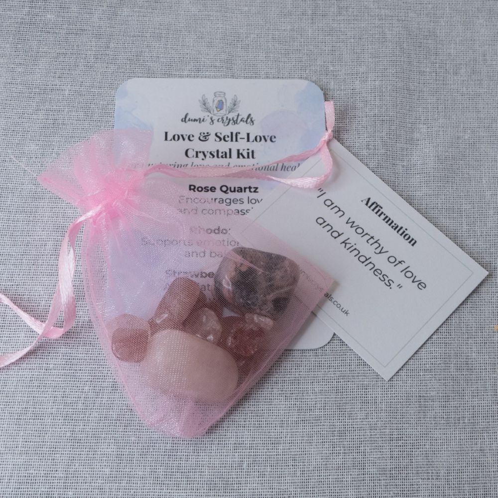 Crystal kit with rose quartz stones in a pink drawstring bag on a gray fabric background
