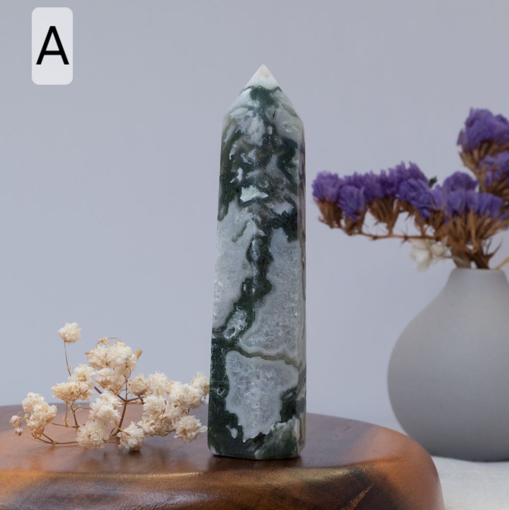 moss agate tower on a wooden surface with flowers and a vase in the background