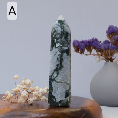 moss agate tower on a wooden surface with flowers and a vase in the background