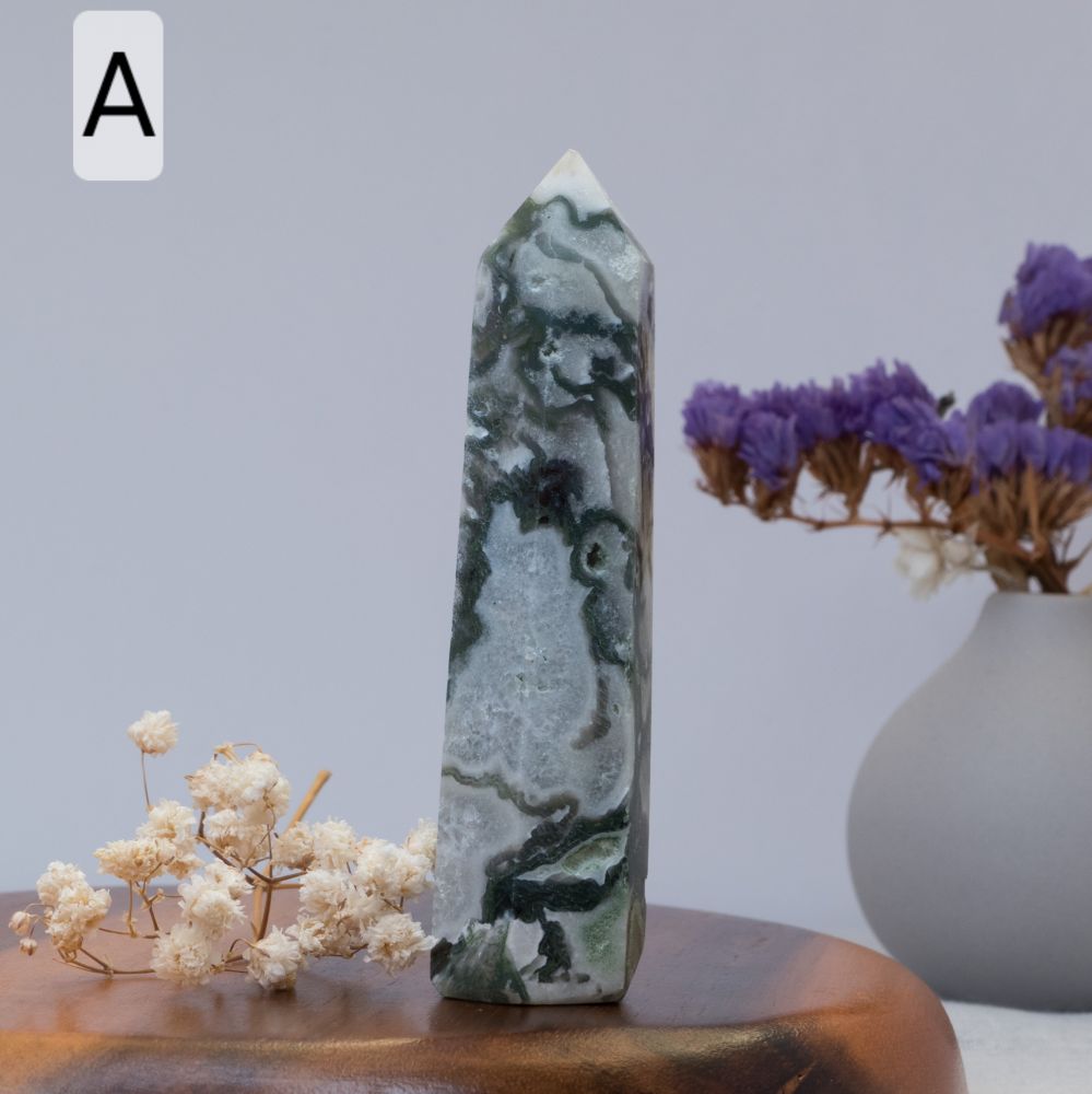 moss agate tower  on a wooden surface with flowers and a vase in the background