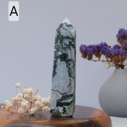 moss agate tower  on a wooden surface with flowers and a vase in the background
