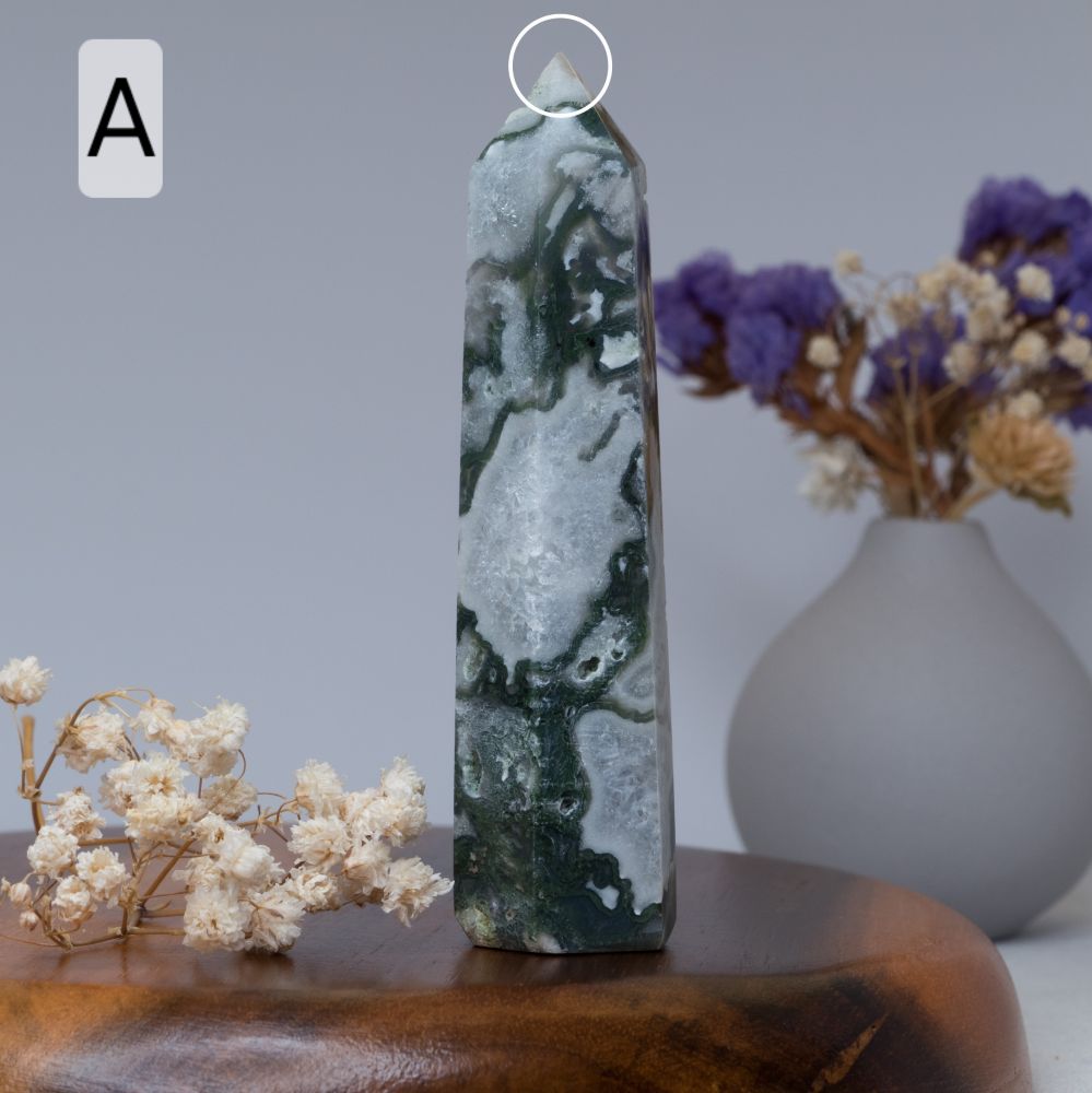 moss agate tower  on a wooden surface with flowers and a vase in the background