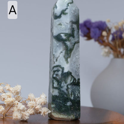 moss agate tower  surrounded by dried flowers on a wooden surface.