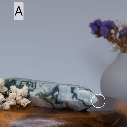 moss agate tower  on a wooden surface with a blurred vase and flowers in the background