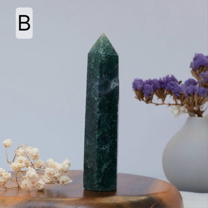 moss agate tower  on a wooden surface with white and purple flowers in the background