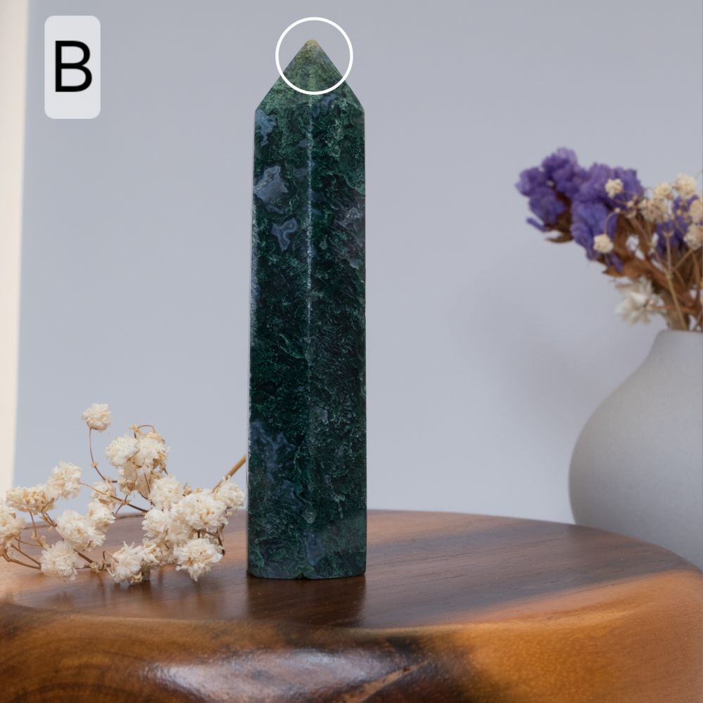 moss agate tower  on a wooden surface with flowers in the background