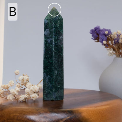 moss agate tower  on a wooden surface with flowers in the background